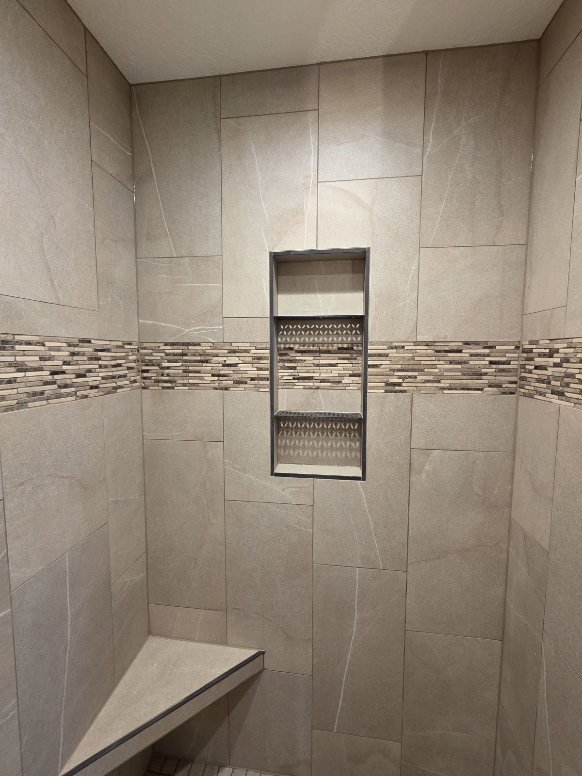 Large-format tile shower with mosaic band, niche and built-in bench