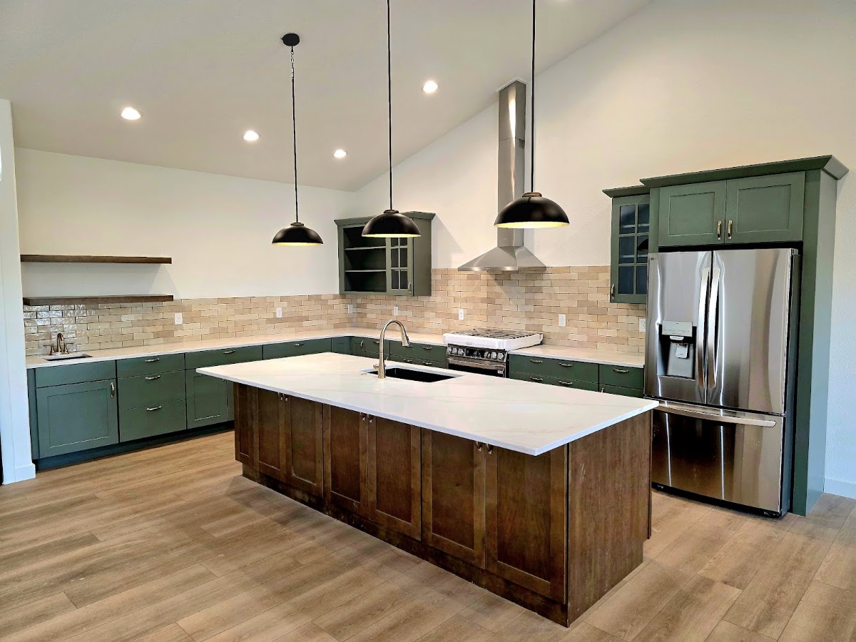 Kitchen with green cabinets, wood island and pendant lights